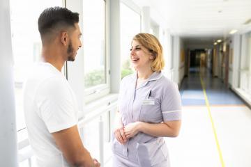 A man and woman talking in a hospital corridor