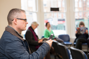 Man in waiting room looking at a mobile phone